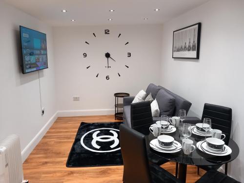 a living room with a table and a clock on the wall at 3 Guests - 1 Bedroom in Erith
