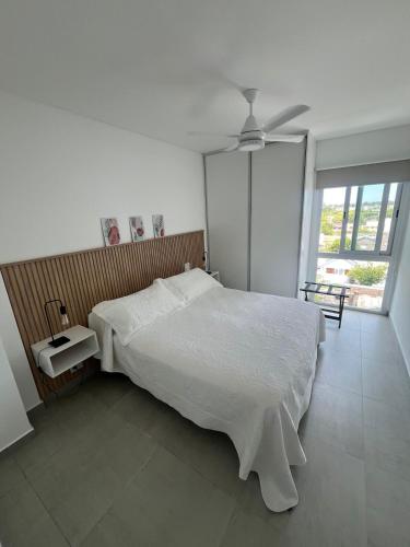 a bedroom with a white bed and a ceiling fan at Depto Yrigoyen, opcional COCHERA a 20 metros in Rafaela