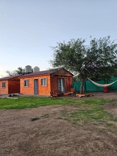 a log cabin with a tree and a tent at Complejo Huayra Huasi in Villa Bustos