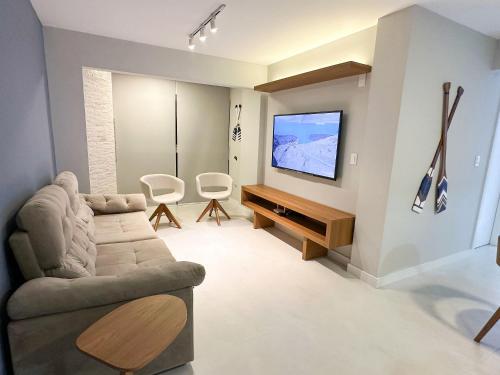 Una sala de estar con un sofá y un televisor de pantalla plana. en Turim, en Balneário Camboriú