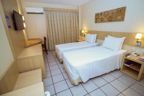 a hotel room with two beds and a television at Hotel Diogo in Fortaleza