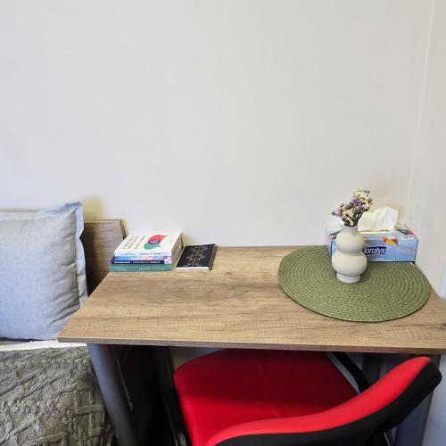 a desk with a red chair and a vase with flowers at MA DONNA rooms in Floreşti