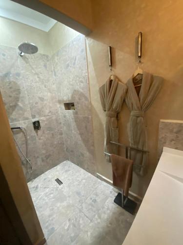 a bathroom with a shower and a robe on a rack at Riad Dar 73 in Marrakech