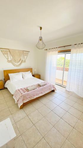 a bedroom with a bed and a large window at Casa Lua Guesthouse in Burgau