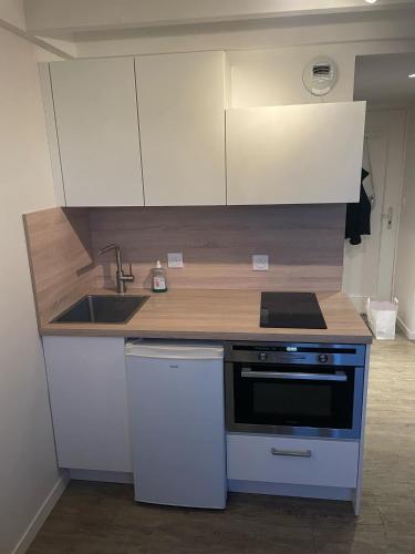 La cuisine est équipée de placards blancs, d'une cuisinière et d'un évier. dans l'établissement Studio sur le Port du Crouesty, à Arzon