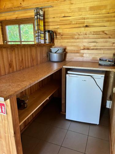 a kitchen with a counter and a white refrigerator at Kempings Paegļi in Kaijciems