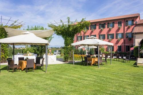 a group of tables and chairs under umbrellas in a yard at Borgo Ronchetto in Salgareda
