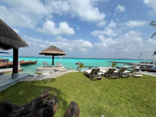 a resort with a lawn with chairs and the ocean at Villa Bianca Bacalar in Bacalar