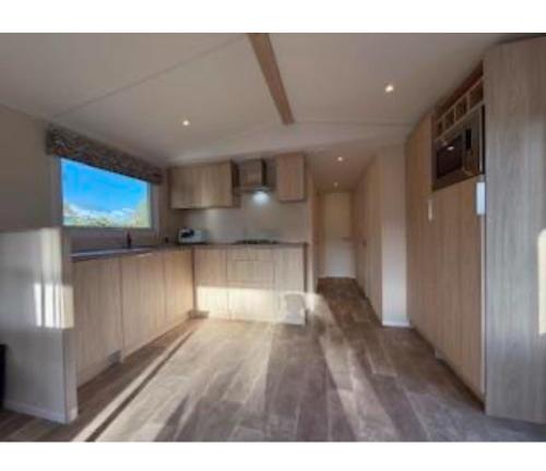 a large kitchen with wooden floors and a large window at Chalet Strandloper in Scharendijke