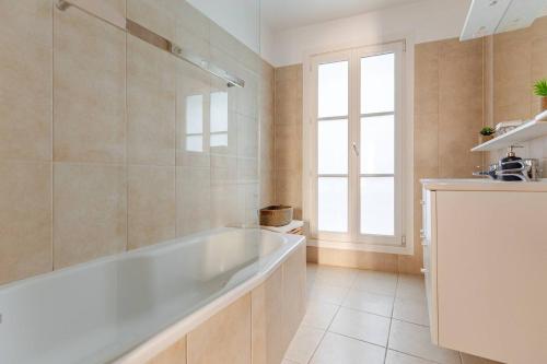 une salle de bain avec une grande baignoire et une fenêtre dans l'établissement La Suite Saint-Germain, à Paris