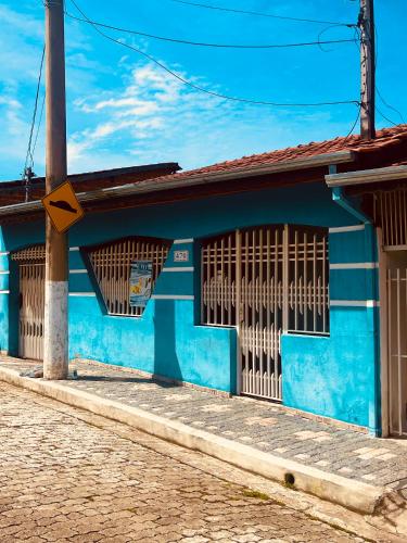 a blue building with barred windows on a street at Casa & Hospedagem Carol in Cachoeira Paulista