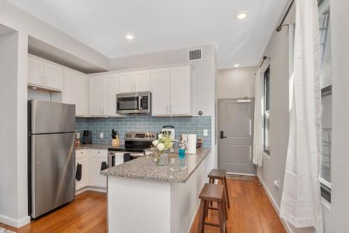 eine Küche mit weißen Schränken und einem Edelstahlkühlschrank in der Unterkunft Sleep like a King - OTR- Free Light Rail ! in Cincinnati