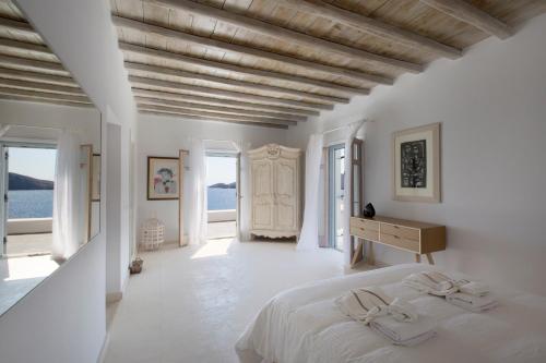 una camera da letto bianca con un letto e una scrivania di CasaDei Pool 4-BDR Sea View Villas 'Anemos' & 'Petra' with Nighttime Security Guard a Panormos - Mykonos
