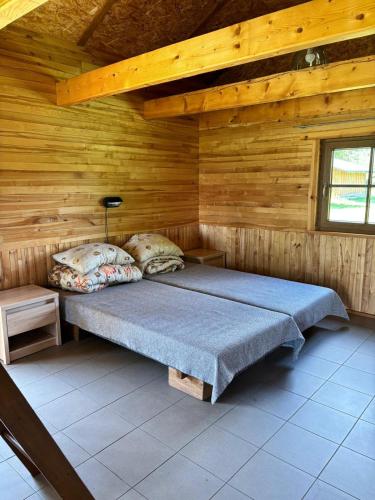 a bedroom with a bed in a wooden cabin at Kempings Paegļi in Kaijciems