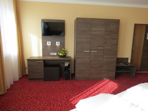 a bedroom with a desk and a dresser at ates Hotel Lampertheim by AURUM in Lampertheim