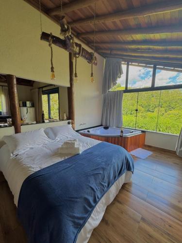 a bedroom with a large bed and a large window at Chalé Choupana - Capim Cidreira in São Bento do Sapucaí