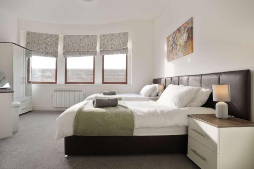 a bedroom with a large bed and two windows at Cosy home in Hull Centre Flat 2 in Hull
