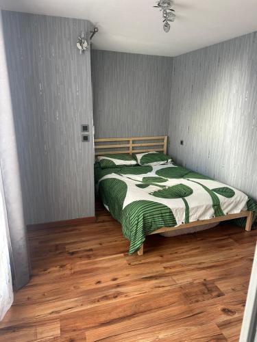 - une chambre avec un lit et une couette verte et blanche dans l'établissement arc en ciel, à Bagnères-de-Bigorre