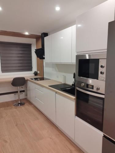 une cuisine avec des armoires blanches et un four à plaques de cuisson dans l'établissement Appartement Cosy, Nantes-St-Herblain, à Saint-Herblain