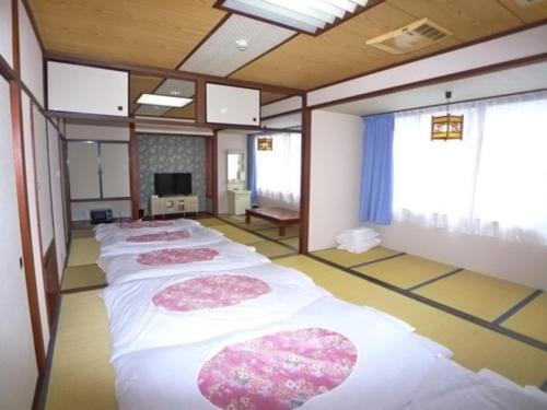 a row of four beds in a room with windows at Hotel Shin Makomo - Vacation STAY 32738v in Itako