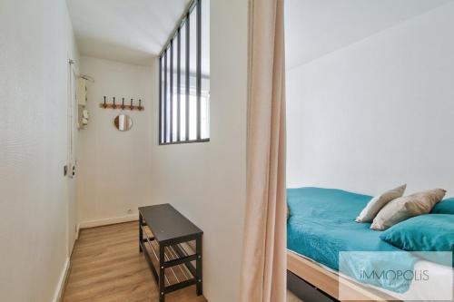 Un dormitorio con una cama azul y una mesa. en Bel appartement avec terrasse, en Clichy