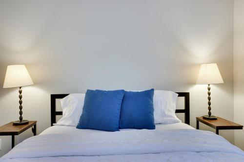 a white bed with blue pillows and two lamps at Dreamy Lake House - Fireplace, Firepit & Pet Friendly in Pocono Lake