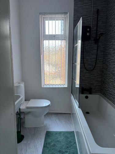 a bathroom with a tub and a toilet and a window at Gertrude house in Saint Helens