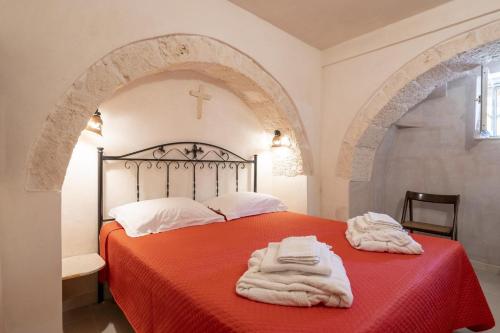 Un dormitorio con una cama roja con una cruz en la pared en Le lamie di Comasia, en Martina Franca