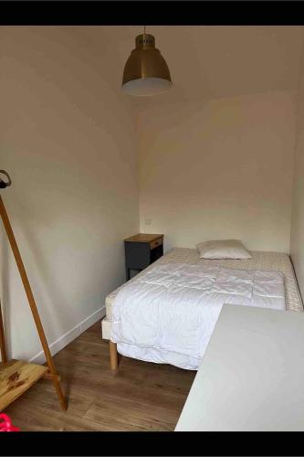 une chambre avec un lit blanc et une table dans l'établissement Maisonnette en bois, à Le Perreux-Sur-Marne