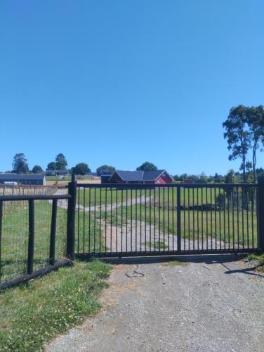 an iron gate with a field behind it at Refugio del viajero, ideal para familias grandes in Puerto Varas