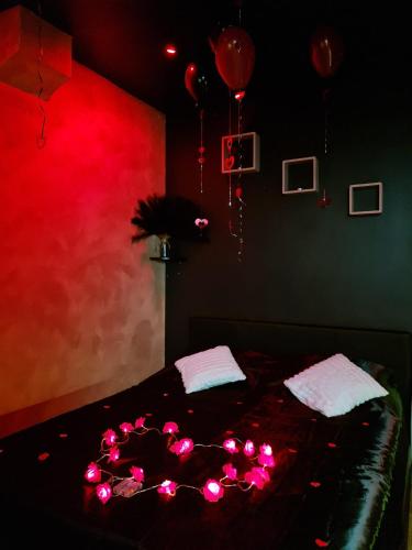 a bedroom with a bed with red lights and balloons at Love Room Jacuzzi in Lyon