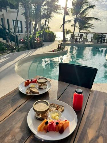 two plates of food on a table next to a pool at Mantaray Tulum in Tulum