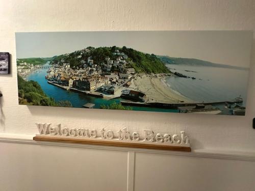 a picture hanging on a wall with a boat in the water at Seaway Beach House Looe Beach in Looe