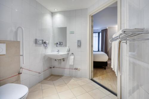 a white bathroom with a sink and a toilet at Holiday Inn Brussels Schuman by IHG in Brussels