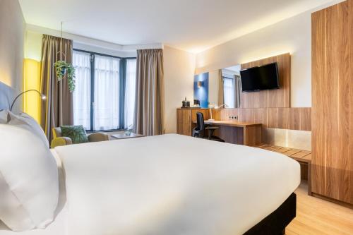 a hotel room with a large bed and a desk at Holiday Inn Brussels Schuman by IHG in Brussels