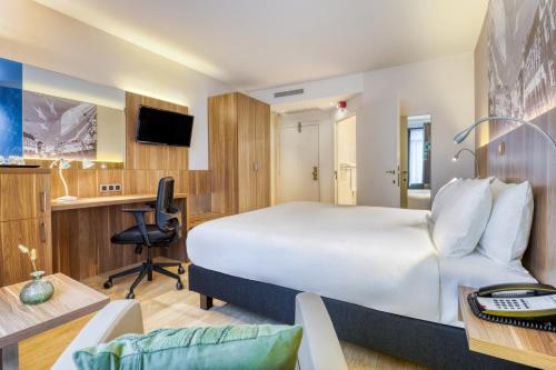 a hotel room with a large bed and a desk at Holiday Inn Brussels Schuman by IHG in Brussels