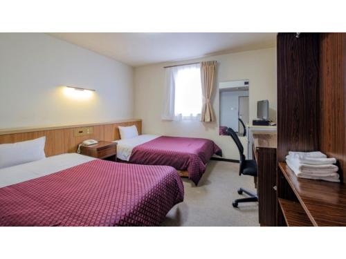 a hotel room with two beds and a desk at Nobeoka Royal Hotel - Vacation STAY 19318v in Nobeoka