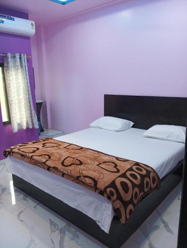 a bedroom with a large bed with a brown blanket at OMKARA GUEST HOUSE Hotel in Ellora