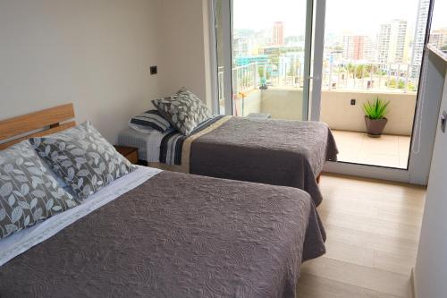 Una habitación de hotel con dos camas y balcón. en Hermoso y moderno departamento, nuevo, a pasos de la Quinta Vergara, cercano a los mejores atractivos de viña del mar, con maravillosa vista, en Viña del Mar