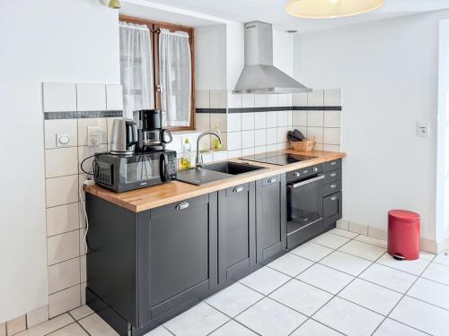 une cuisine avec un évier et un micro-ondes dans l'établissement Gîte Mourniac cœur village - Corrèze - 3ch - 6pers, à Saint-Pantaléon-de-Lapleau