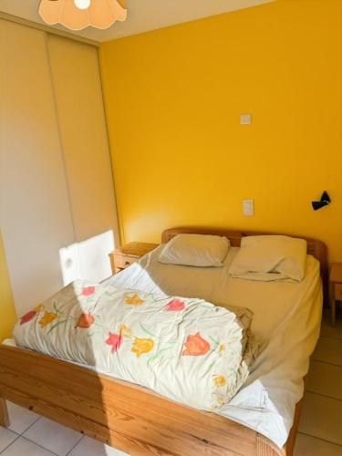 a bed in a room with a yellow wall at Gîte des Combes - Corrèze - 3ch - 10 pers in Saint-Pantaléon-de-Lapleau
