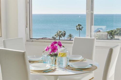 a table with white chairs and a table with flowers on it at La Cala Mijas Esmeralda Stunning Sea Views close to the Beach in La Cala de Mijas