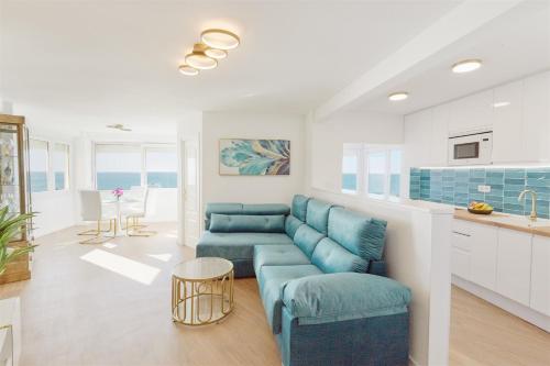 a living room with a blue couch and a kitchen at La Cala Mijas Esmeralda Stunning Sea Views close to the Beach in La Cala de Mijas