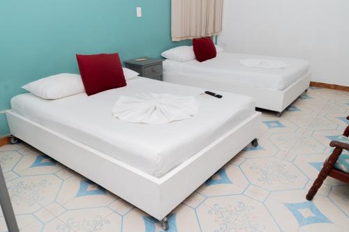 two beds with red and white pillows in a room at Casa Colonial Tulum in Tulum
