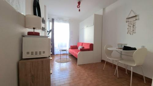 un salon avec un canapé rouge et une table dans l'établissement Studio Cozy en Bord de Plage avec Vue Mer et Wifi, à Canet