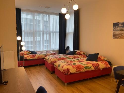 two beds in a room with two windows at Aristoteles Apartments in Scheveningen