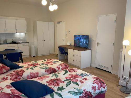 a bedroom with two beds and a desk with a television at Aristoteles Apartments in Scheveningen