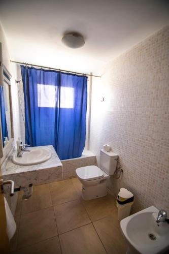 a bathroom with a toilet and a sink with a blue curtain at Cotillo Cala II in El Cotillo