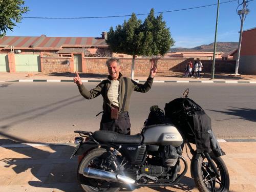 a man is standing next to a motorcycle at riad lala fatima in Ouzoud