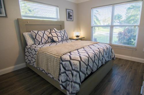 Un dormitorio con una cama y dos ventanas en Lakefront and Pool 4bed Orlando House Near Downtown 20 minutes from Attractions, en Orlando